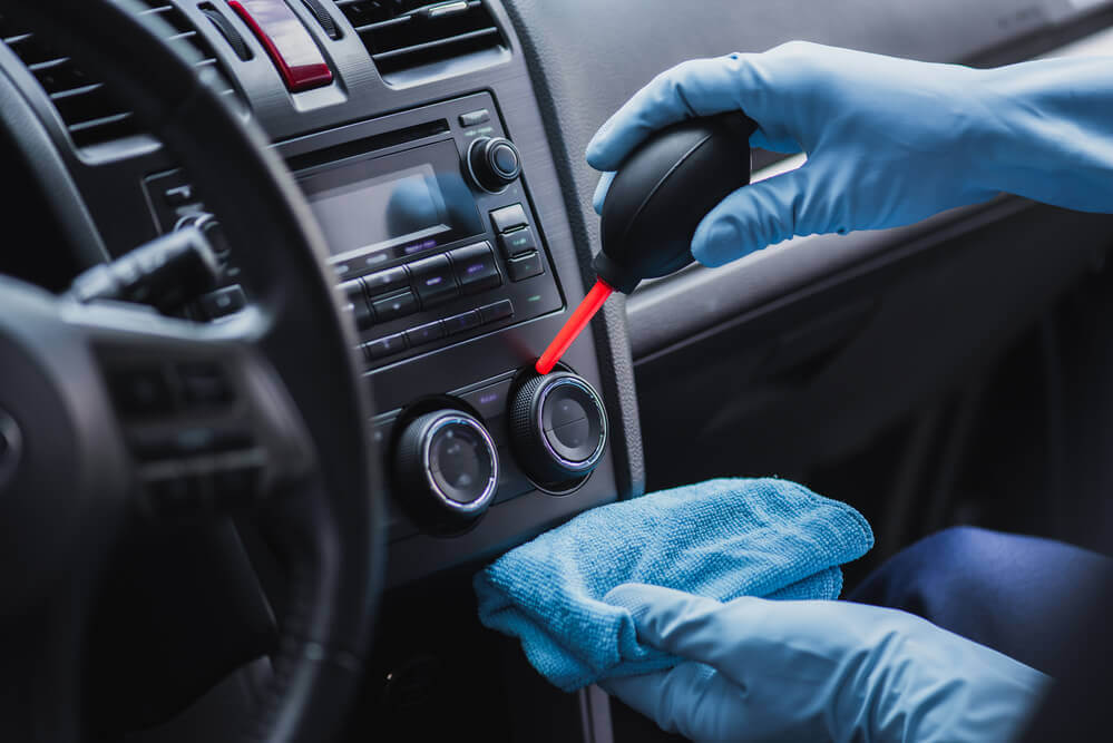 view of a cars dash being cleaned with a hand held air blower